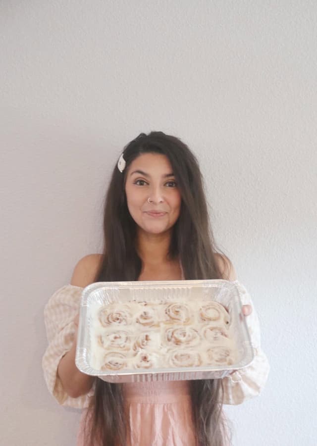 Ellie holding a pan of iced cinnamon rolls
